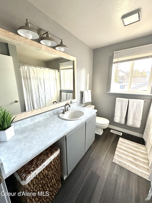 bathroom with visible vents, toilet, wood finished floors, a textured ceiling, and vanity