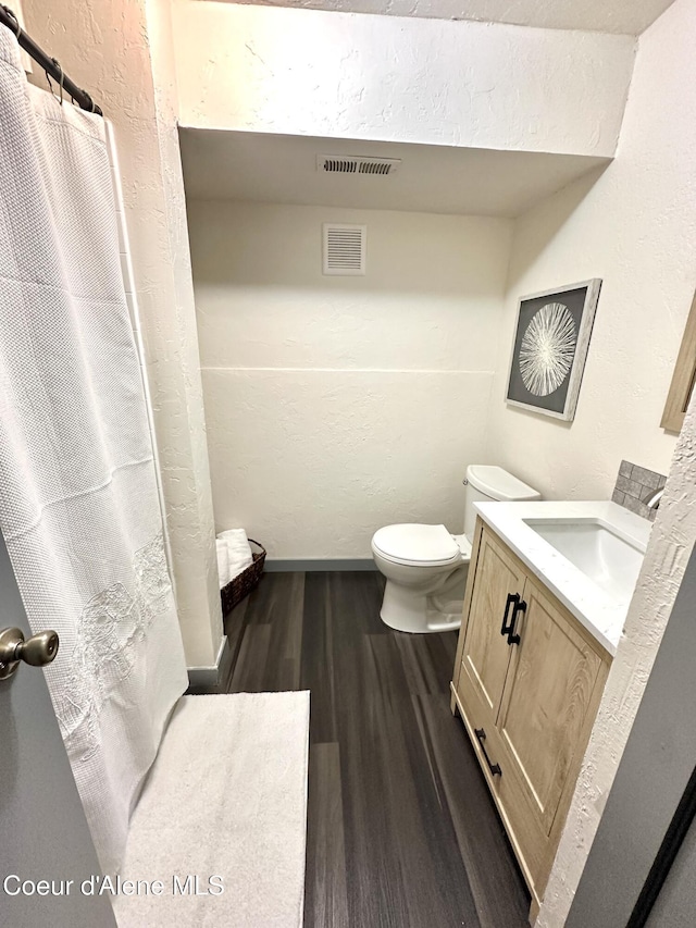 full bath with toilet, vanity, wood finished floors, and visible vents