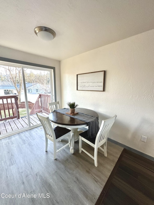 dining space featuring a textured wall, a textured ceiling, and wood finished floors