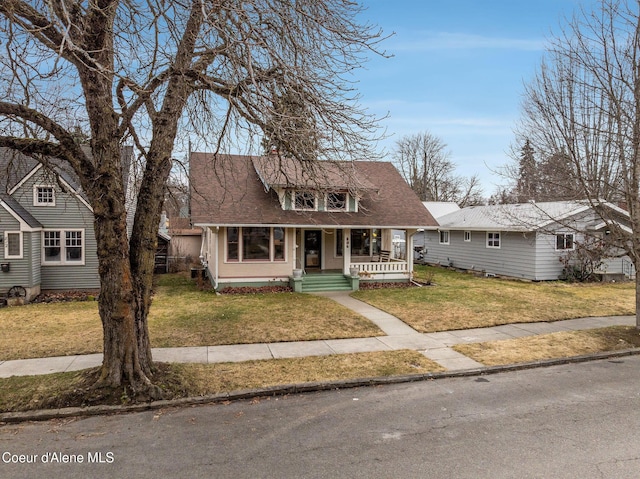 view of front facade featuring a porch, a front yard, and roof with shingles