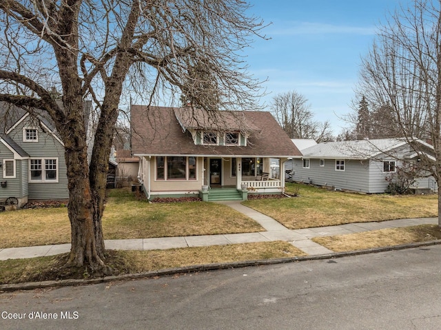 view of front of property featuring a shingled roof, a front lawn, and a porch