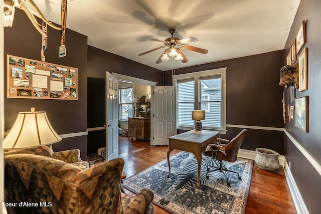 office space featuring a healthy amount of sunlight, ceiling fan, baseboards, and wood finished floors