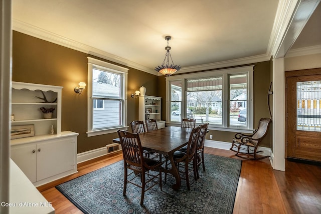 dining space with plenty of natural light, visible vents, dark wood finished floors, and ornamental molding