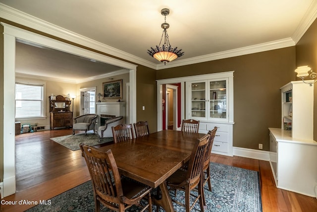 dining area featuring crown molding, baseboards, and wood finished floors