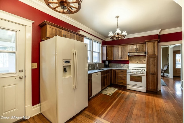 kitchen with a notable chandelier, ornamental molding, a sink, white appliances, and under cabinet range hood