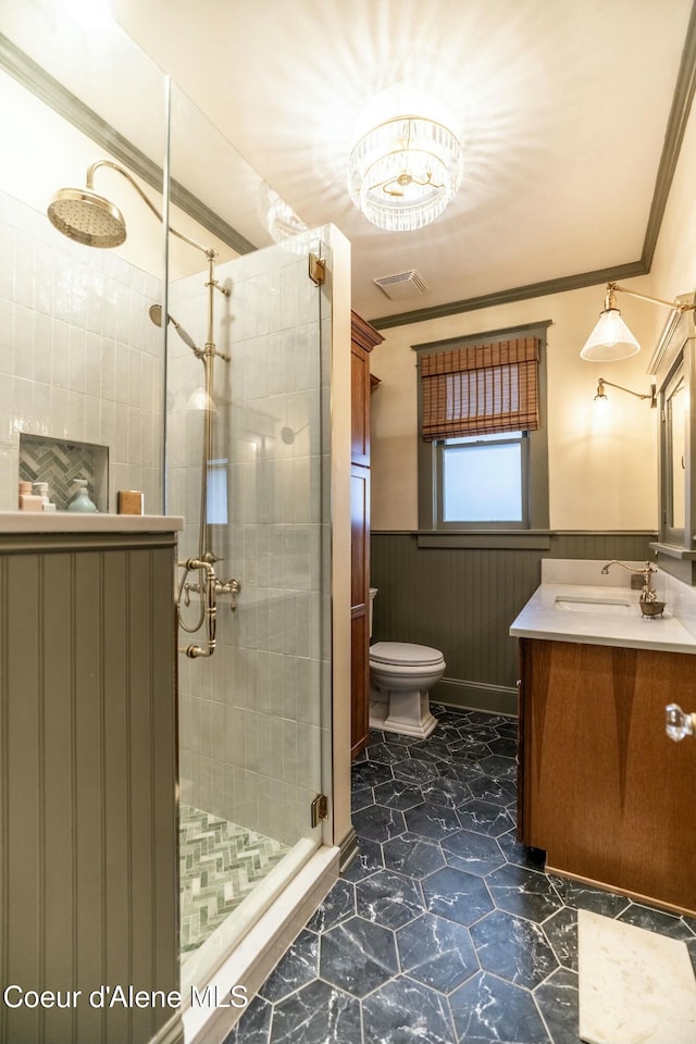 full bathroom featuring a stall shower, visible vents, wainscoting, crown molding, and vanity