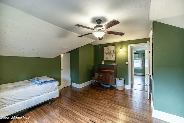 bedroom featuring a ceiling fan, lofted ceiling, baseboards, and wood finished floors