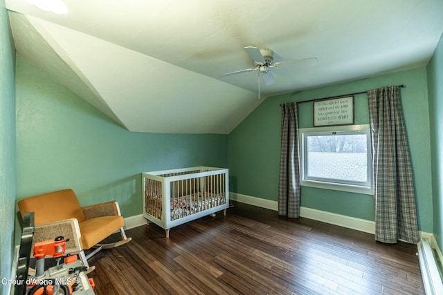 bedroom featuring lofted ceiling, a crib, baseboards, and wood finished floors