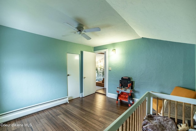 unfurnished bedroom with a textured wall, baseboard heating, a ceiling fan, wood finished floors, and baseboards