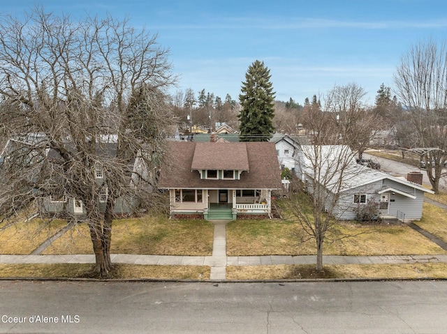 view of front of house with covered porch, roof with shingles, and a front yard