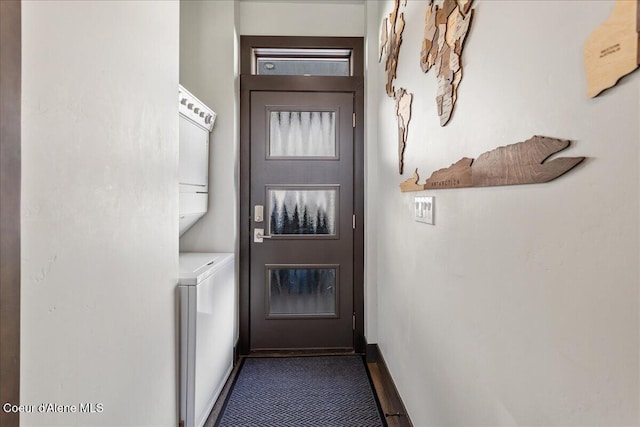 laundry area with laundry area, stacked washer and clothes dryer, and baseboards