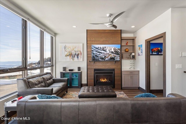 living area featuring baseboards, ceiling fan, wood finished floors, a fireplace, and recessed lighting