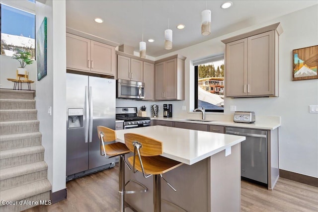 kitchen with appliances with stainless steel finishes, light countertops, a sink, and light wood-style flooring