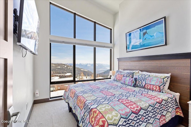 carpeted bedroom featuring a high ceiling and baseboards