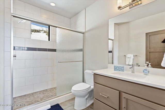 full bath with tiled shower, vanity, and toilet