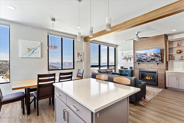 kitchen featuring beamed ceiling, light wood-type flooring, a fireplace, and a center island