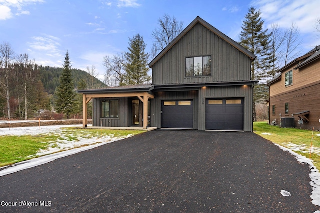 chalet / cabin with an attached garage, central AC unit, and aphalt driveway