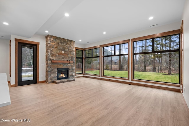 unfurnished living room with recessed lighting, visible vents, a fireplace, and light wood finished floors