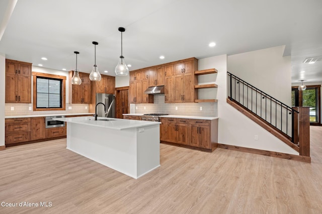 kitchen featuring brown cabinetry, visible vents, under cabinet range hood, and open shelves