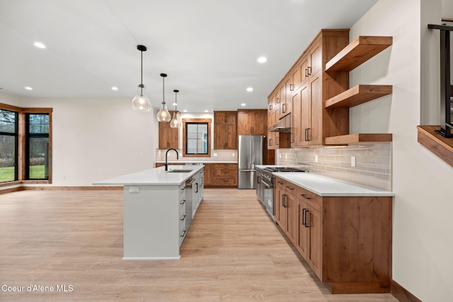 kitchen with an island with sink, brown cabinets, stainless steel appliances, under cabinet range hood, and open shelves