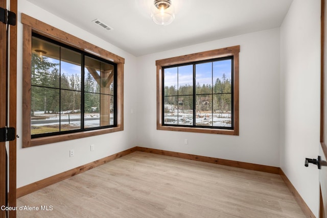 empty room with light wood-type flooring, baseboards, and visible vents