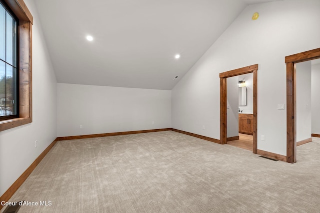 additional living space featuring carpet floors, lofted ceiling, a healthy amount of sunlight, and baseboards