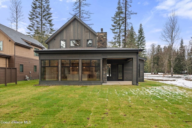 back of property with a sunroom, a lawn, and a chimney