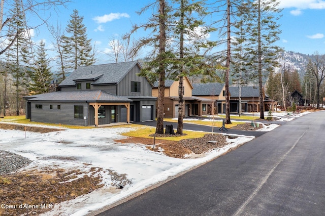 modern inspired farmhouse with aphalt driveway, a porch, an attached garage, roof with shingles, and board and batten siding