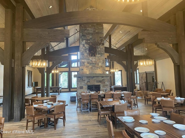 dining room with arched walkways, beam ceiling, a fireplace, and an inviting chandelier