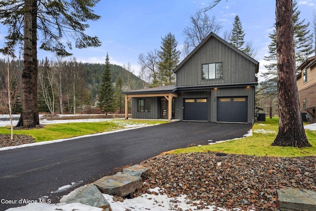 view of front facade featuring driveway, a garage, a mountain view, and a front yard