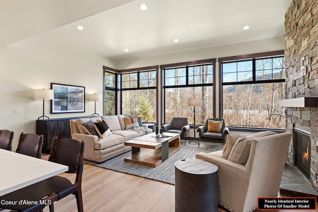 living area featuring a stone fireplace, wood finished floors, and recessed lighting