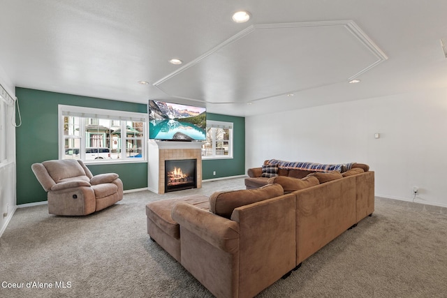 living area featuring plenty of natural light, a tiled fireplace, carpet, and baseboards