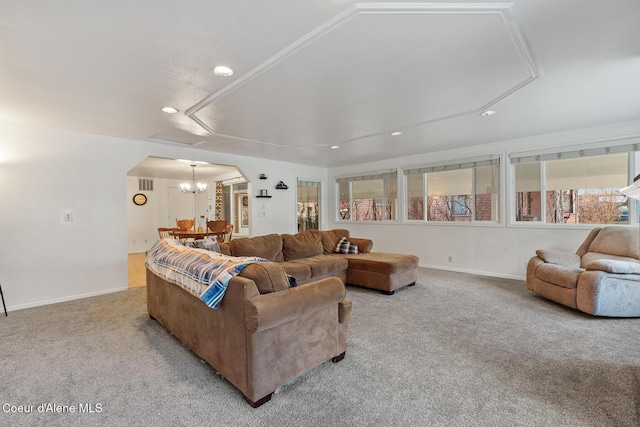 living room featuring carpet floors, baseboards, arched walkways, and a chandelier