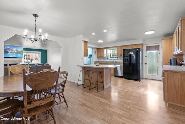 dining room with a notable chandelier, a fireplace, light wood finished floors, recessed lighting, and baseboards