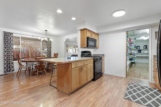 kitchen featuring a kitchen breakfast bar, light countertops, light wood-type flooring, black appliances, and an inviting chandelier