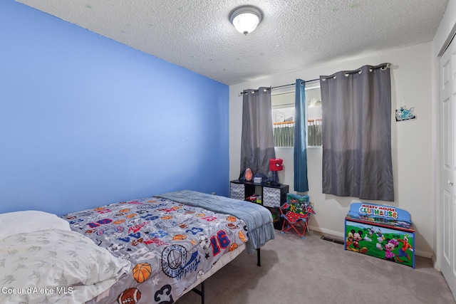 bedroom featuring baseboards, a textured ceiling, visible vents, and carpet flooring