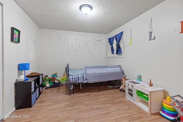 bedroom with light wood-type flooring and a textured ceiling