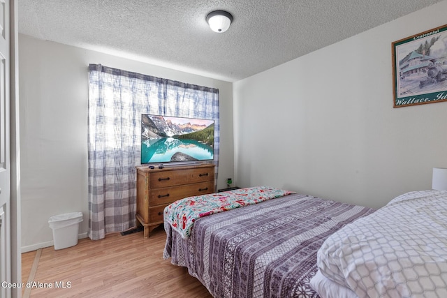 bedroom featuring a textured ceiling and light wood finished floors