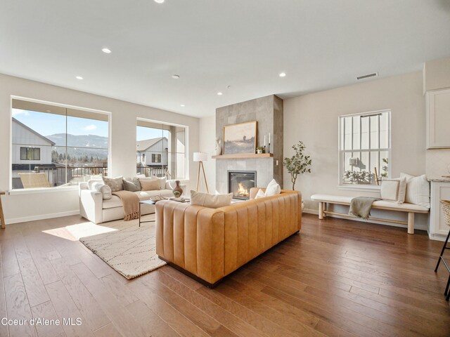 living room featuring recessed lighting, a fireplace, visible vents, and wood-type flooring