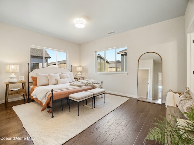 bedroom featuring arched walkways, visible vents, baseboards, and dark wood-style flooring