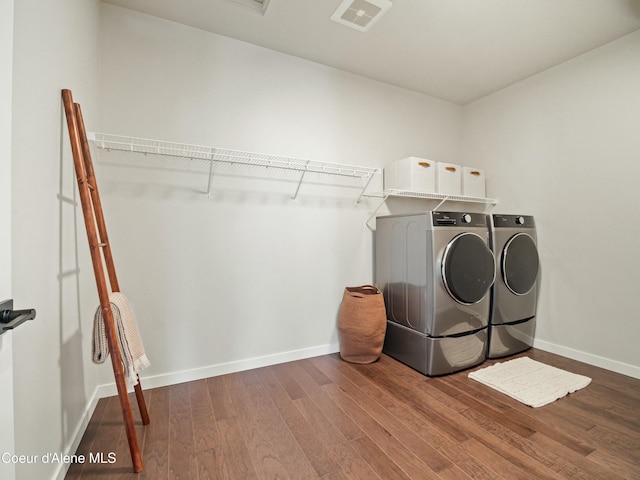 laundry area with visible vents, baseboards, laundry area, wood finished floors, and washer and dryer