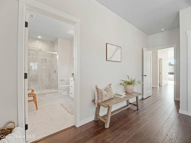 hallway featuring visible vents, baseboards, and dark wood finished floors