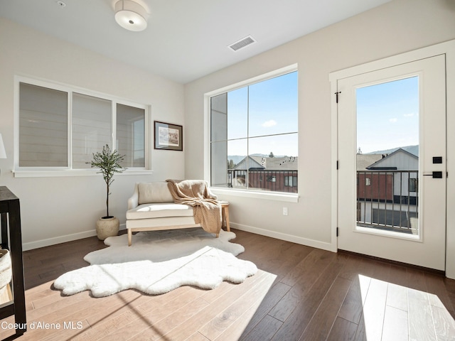 living area featuring visible vents, baseboards, and hardwood / wood-style flooring