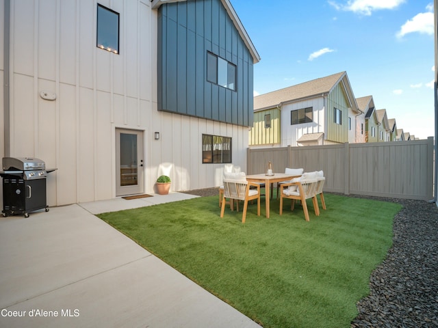 back of property with a yard, a patio, board and batten siding, and fence