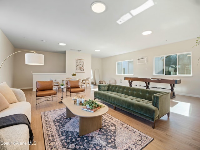 living area with baseboards, light wood-style flooring, recessed lighting, arched walkways, and an AC wall unit