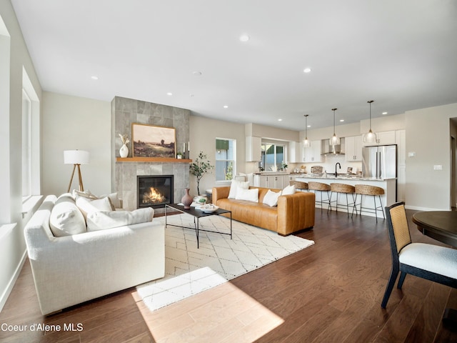 living area featuring recessed lighting, a fireplace, baseboards, and wood finished floors