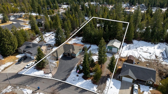 snowy aerial view featuring a view of trees and a residential view