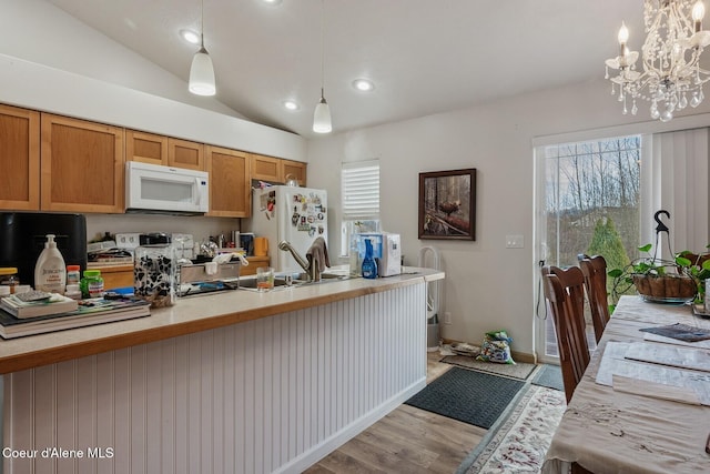 kitchen featuring light wood-type flooring, decorative light fixtures, white appliances, light countertops, and vaulted ceiling