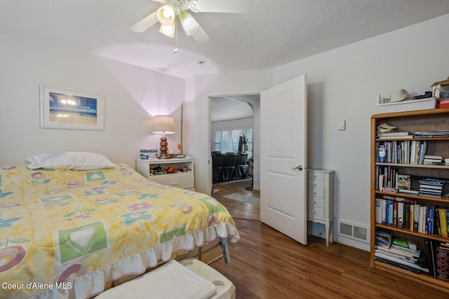 bedroom with ceiling fan, visible vents, baseboards, and wood finished floors