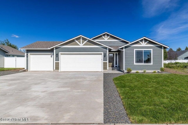 view of front of property featuring driveway, an attached garage, fence, and a front yard